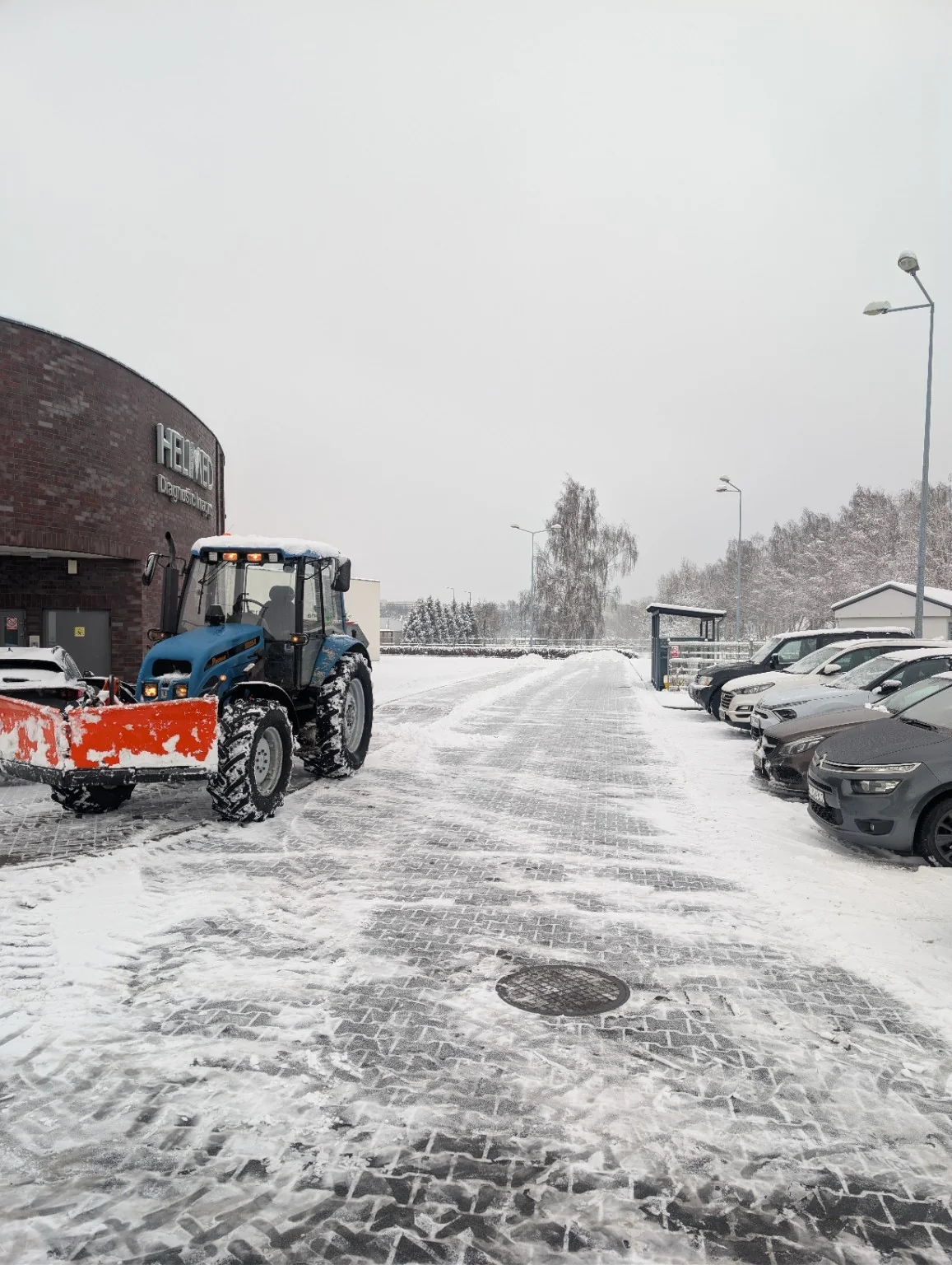 Ciągnik z pługiem podczas zimowego utrzymania parkingu